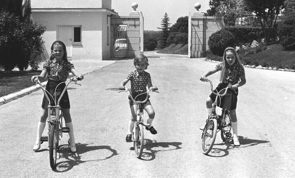 1979. Madrid, Palace of the Zarzuela, Spain. The three children of the Princes of Spain Elena, Cristina and Felipe riding a bicycle in the gardens of the Palace.